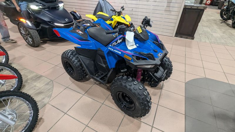 2025 POLARIS OUTLAW 70 EFI  VELOCITY BLUE AND FIERCE FUCHSIA in a VELOCITY BLUE AND FIERCE FUCHSIA exterior color. Family PowerSports (877) 886-1997 familypowersports.com 