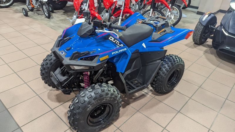 2025 POLARIS OUTLAW 70 EFI  VELOCITY BLUE AND FIERCE FUCHSIA in a VELOCITY BLUE AND FIERCE FUCHSIA exterior color. Family PowerSports (877) 886-1997 familypowersports.com 