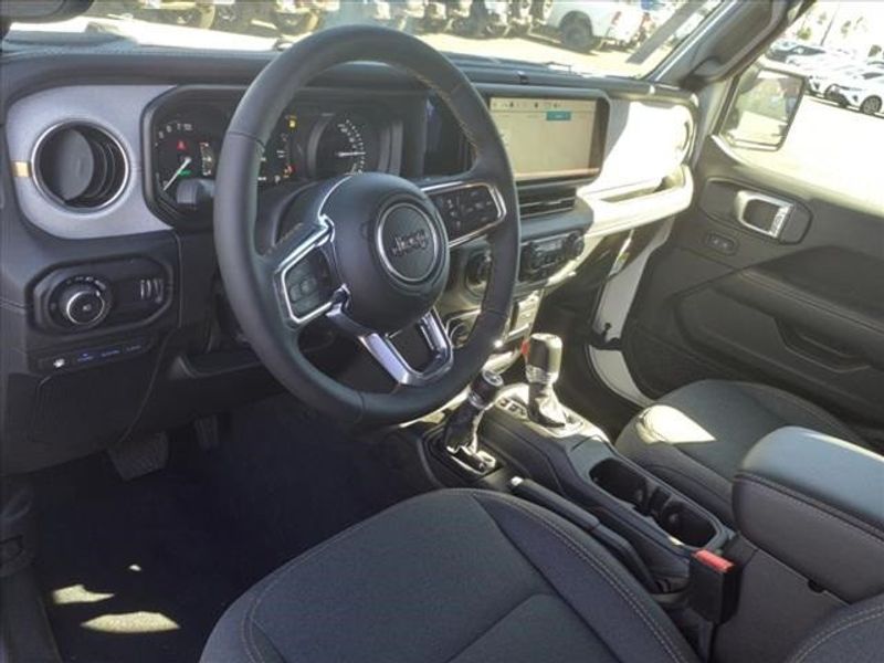 2024 Jeep Wrangler Sahara 4xe in a Bright White Clear Coat exterior color and Blackinterior. Perris Valley Auto Center 951-657-6100 perrisvalleyautocenter.com 