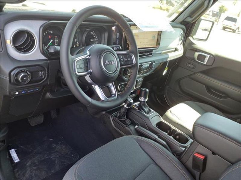 2024 Jeep Wrangler Sahara 4xe in a Black Clear Coat exterior color and Blackinterior. Perris Valley Auto Center 951-657-6100 perrisvalleyautocenter.com 