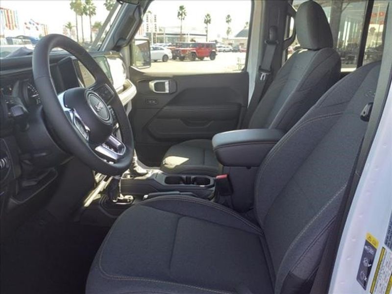 2024 Jeep Wrangler Sahara 4xe in a Bright White Clear Coat exterior color and Blackinterior. Perris Valley Auto Center 951-657-6100 perrisvalleyautocenter.com 